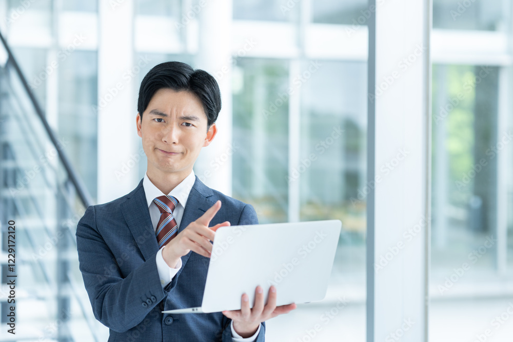 オフィスでパソコンを持つ若いビジネスマン オフィスでパソコンを持つ若いビジネスマン