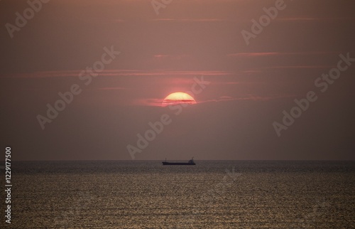 Cargo ship in the Mediterranean Sea under the evening sun, photographed from the beach near Tarragona, Catalonia, Spain, Europe