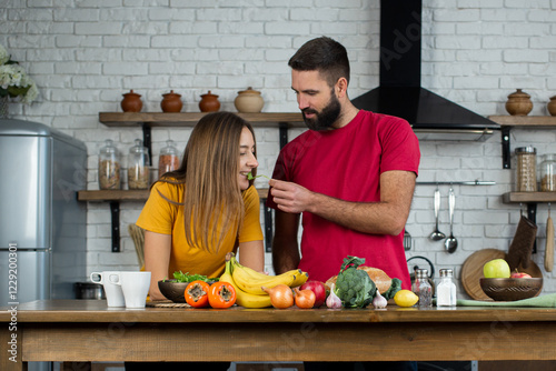 Attractive couple is cooking together organic healthy food in kitchen. Excited happy young couple in love cooking in the kitchen and having fun together while making fresh healthy salad.