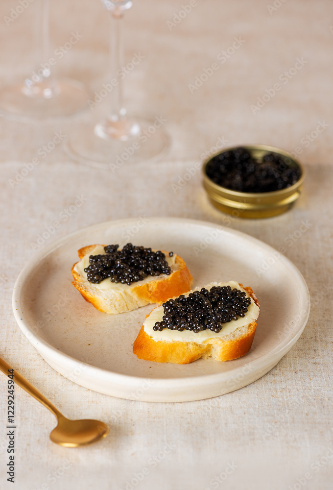 Sandwiches with black caviar and glasses of wine. Sturgeon black caviar in plate, sandwiches and champagne on table. Vertical orientation. Sandwiches with black caviar and glasses of wine. Sturgeon black caviar in plate, sandwiches and champagne on table. Vertical orientation.