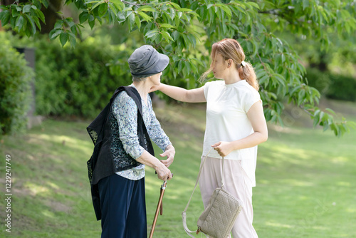 At grass area of A park with good atmosphere with canal in Toyama Prefecture. Old woman in her 90s and Japanese woman in her thirties are walking around the park. photo