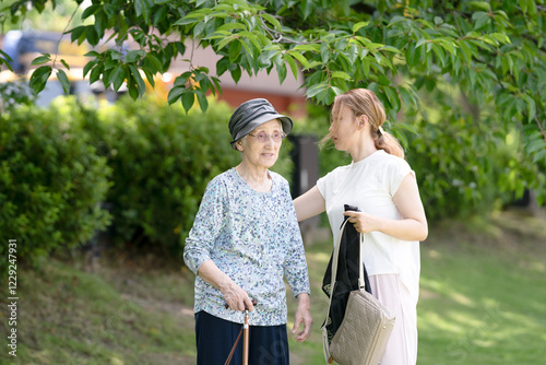 At grass area of A park with good atmosphere with canal in Toyama Prefecture. Old woman in her 90s and Japanese woman in her thirties are walking around the park. photo