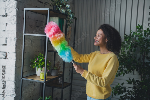 Young woman cleaning with a colorful duster in a cozy home interior