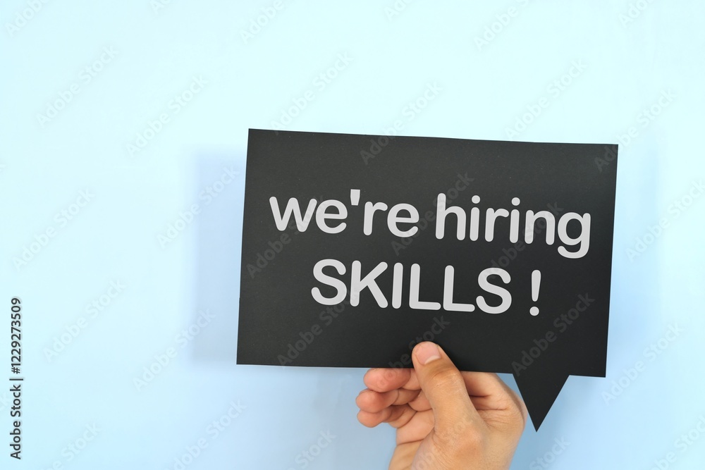 Human hand holding yellow speech bubble with written phrase we are hiring skills.