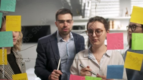 Young Business Team Brainstorming. Business Woman Draws a Graph On Glass Wall With Stickers. Colleagues Approve. Business Success Concept photo