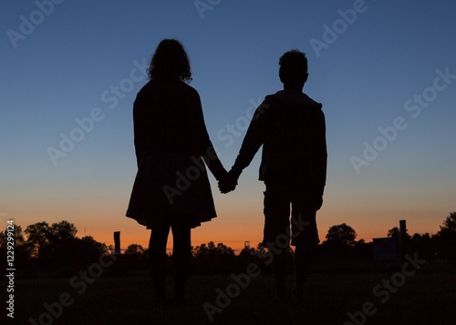 Silhouette in front of evening sky, two children holding hands, Germany, Europe