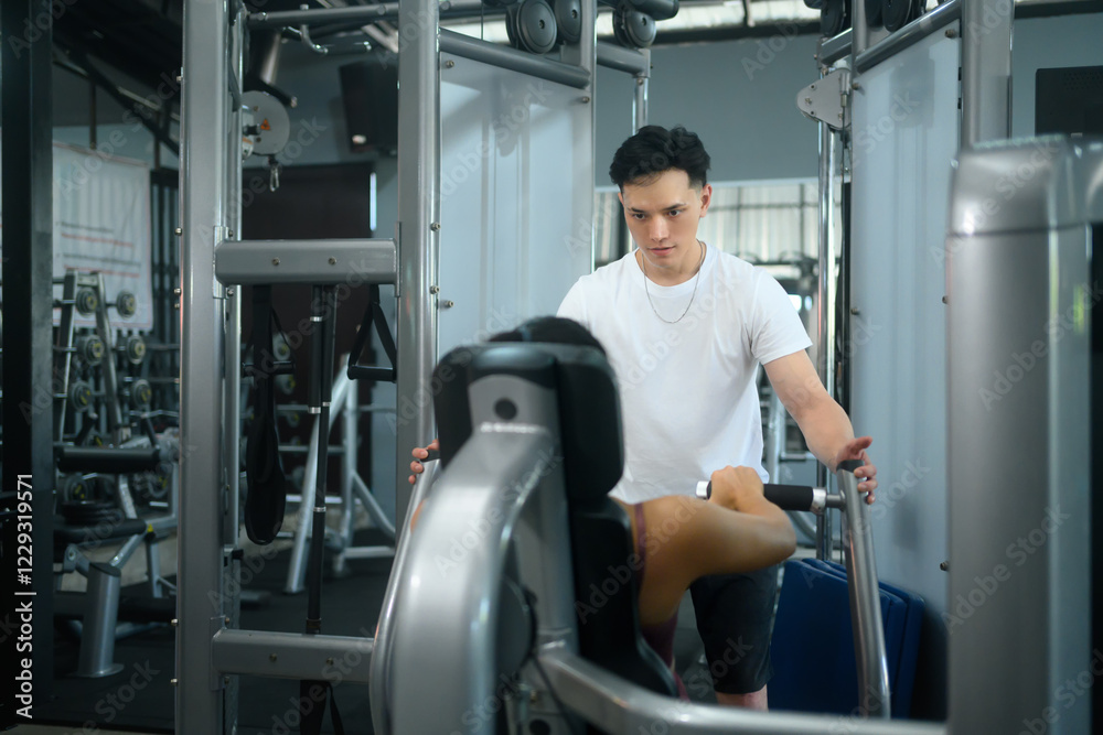 Personal trainer closely assisting a female client during exercise in a modern gym Personal trainer closely assisting a female client during exercise in a modern gym