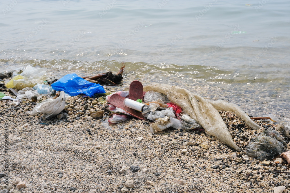 Garbage trash rubbish waste being washed to the shoreline by sea waves.