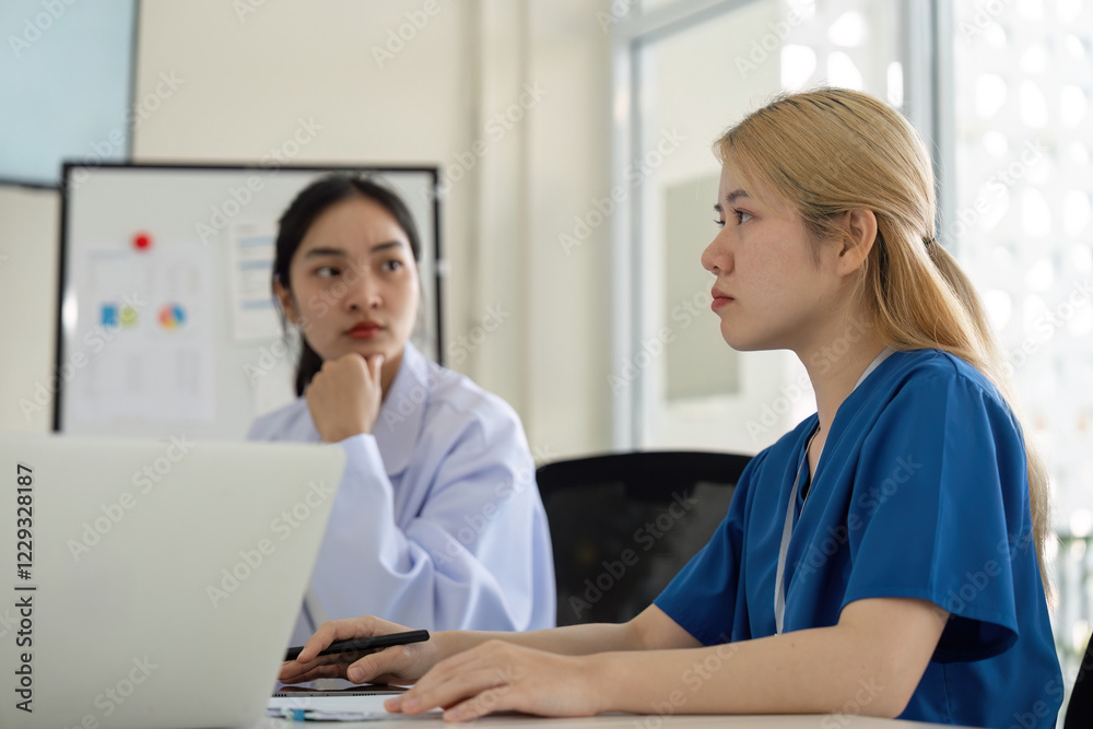 Fototapeta premium Diverse female healthcare professionals engaged in a focused discussion during a team meeting.