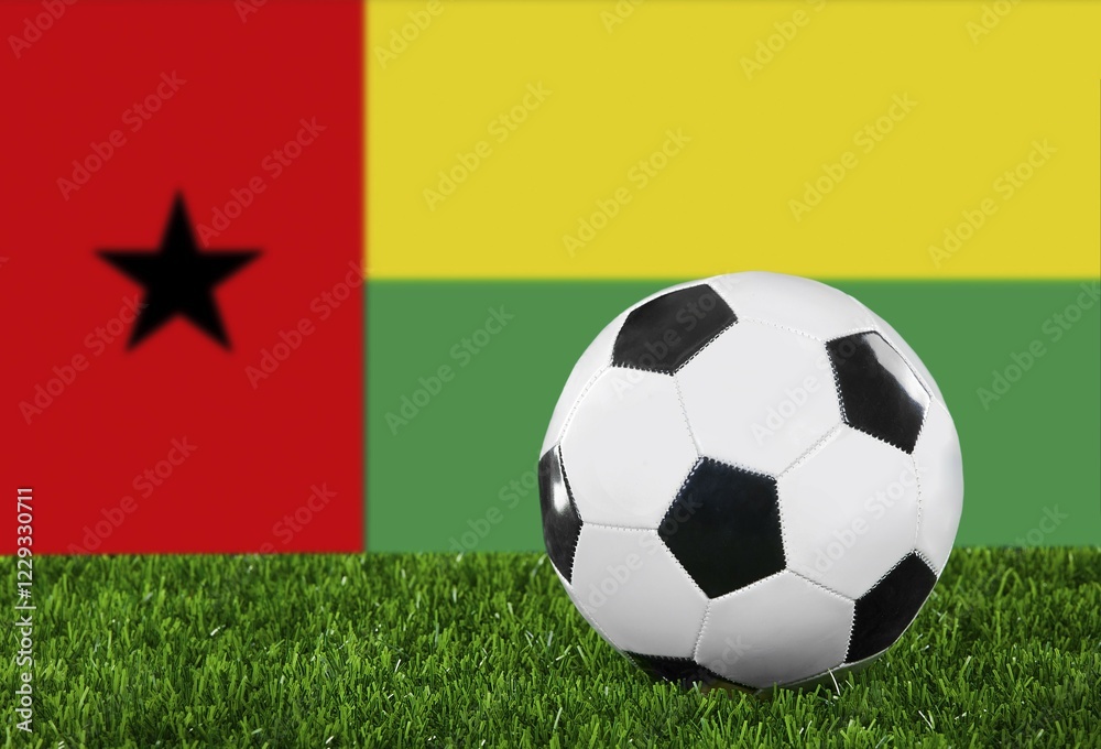 Fototapeta premium The Guinea-Bissau Flag and soccer ball on the green grass