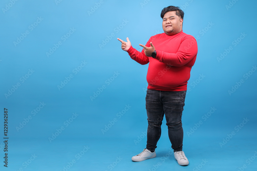 Full Length Shot Of Fat Man Presenting Ads On The Side On Blue Studio Wall Full Length Shot Of Fat Man Presenting Ads On The Side On Blue Studio Wall