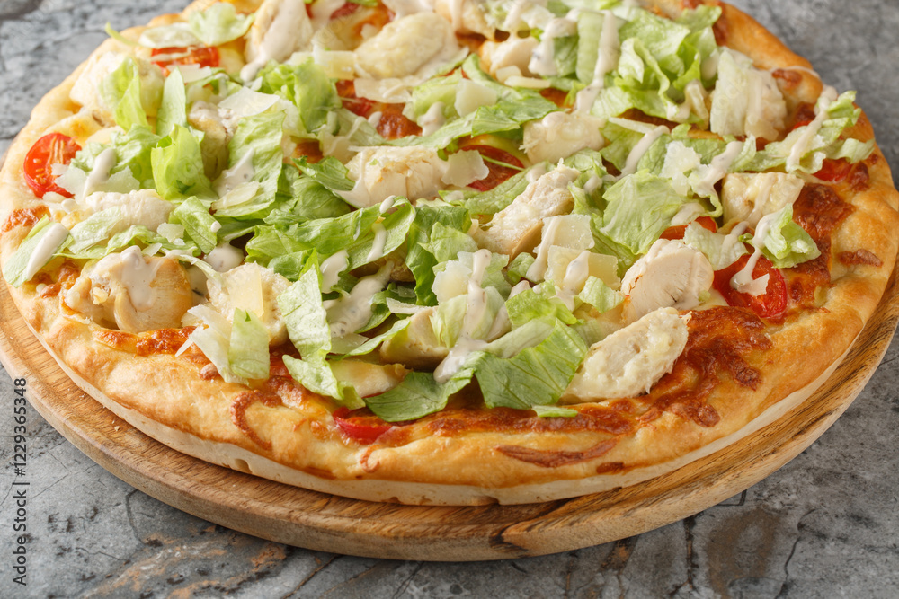 Caesar style pizza with chicken, lettuce, tomatoes, cheese and Caesar dressing closeup on the wooden board on the table. Horizontal