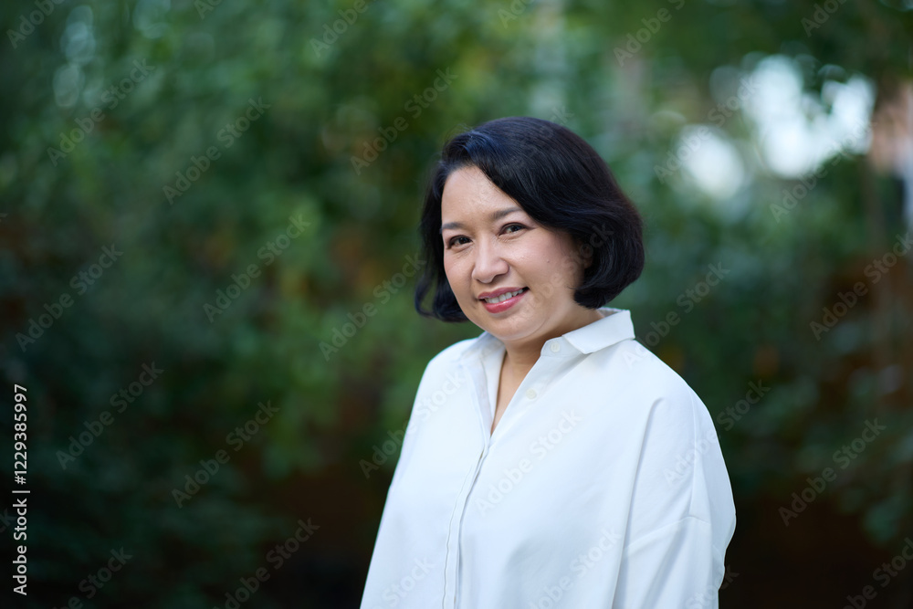 Portrait of smiling middle aged Asian business women in natural background Portrait of smiling middle aged Asian business women in natural background