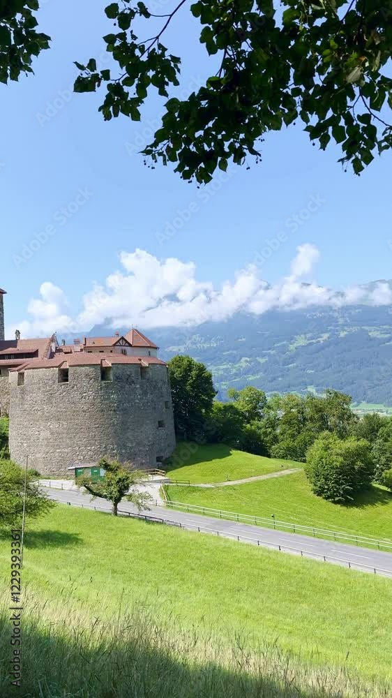 Vertical Shot of Vaduz Castle in Liechtenstein Overlooking Green Meadow and Mountains Vertical Shot of Vaduz Castle in Liechtenstein Overlooking Green Meadow and Mountains