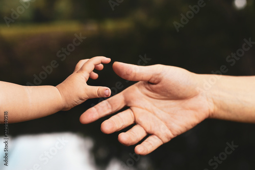 two hands of mother and baby reach to each other with river photo