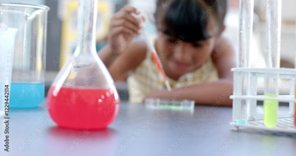 In a school classroom, a young biracial student examines a chemical reaction In a school classroom, a young biracial student examines a chemical reaction