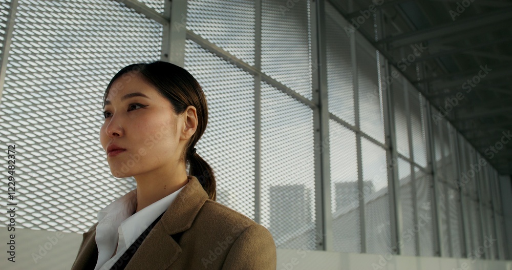 A woman in a coat looks at the camera with a concentrated look standing at the train station, close-up of her face A woman in a coat looks at the camera with a concentrated look standing at the train station, close-up of her face