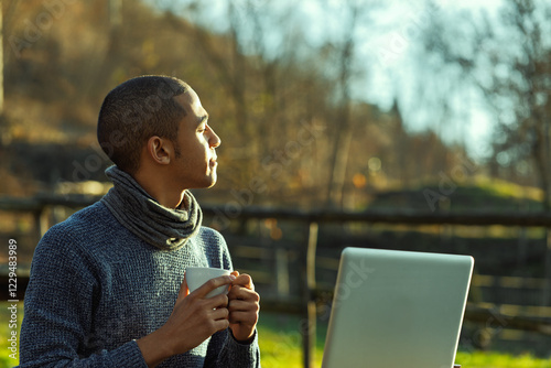 Young freelancer enjoying a coffee break in nature with laptop