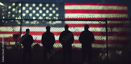American immigration and United States refugee crisis concept as Mexican people on a USA border. Mexican people stare out the fence with USA flag. USA-Mexico border crisis.