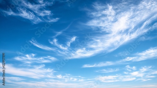 White wispy clouds in bright blue sky. Suitable for weather themes, natural backgrounds, and environmental concepts.