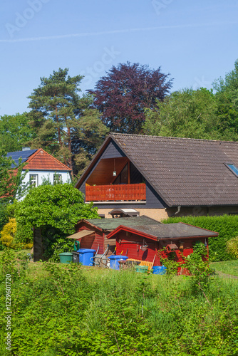 Wohnhaus mit Gartenlauben und Mülltonnen am Fluss Wörpe im Frühling, Lilienthal, Niedersachsen, Deutschland photo