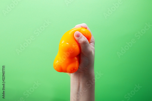 Hand squeeze orange stress ball on green background. Positive thinking concept photo