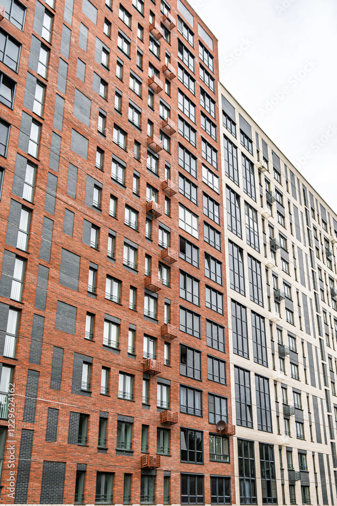 Modern multi-story buildings with beige, red brick and glass facades, showcasing balconies and windows. Urban architecture concept, low angle view Modern multi-story buildings with beige, red brick and glass facades, showcasing balconies and windows. Urban architecture concept, low angle view