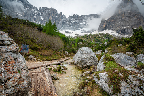 Obraz na płótnie Rocky hiking trail near Lago Sorapis in the Dolomites (Dolomiti, Dolomiten), Italy. The path runs alongside a small mountain stream, with massive boulders and peaks in the background w salonie