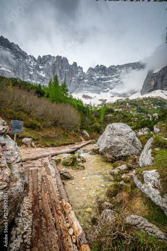Obraz na płótnie Rocky hiking trail near Lago Sorapis in the Dolomites (Dolomiti, Dolomiten), Italy. The path runs alongside a small mountain stream, with massive boulders and peaks in the background w salonie