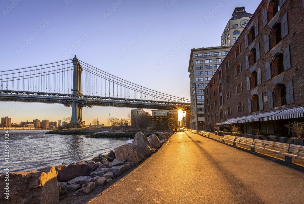 Fototapeta premium Manhattan Bridge in Backlight, Morning Sun, Sun Star, Sunrise, Empire Fulton Ferry Park, Dumbo, Brooklyn, New York, USA, North America