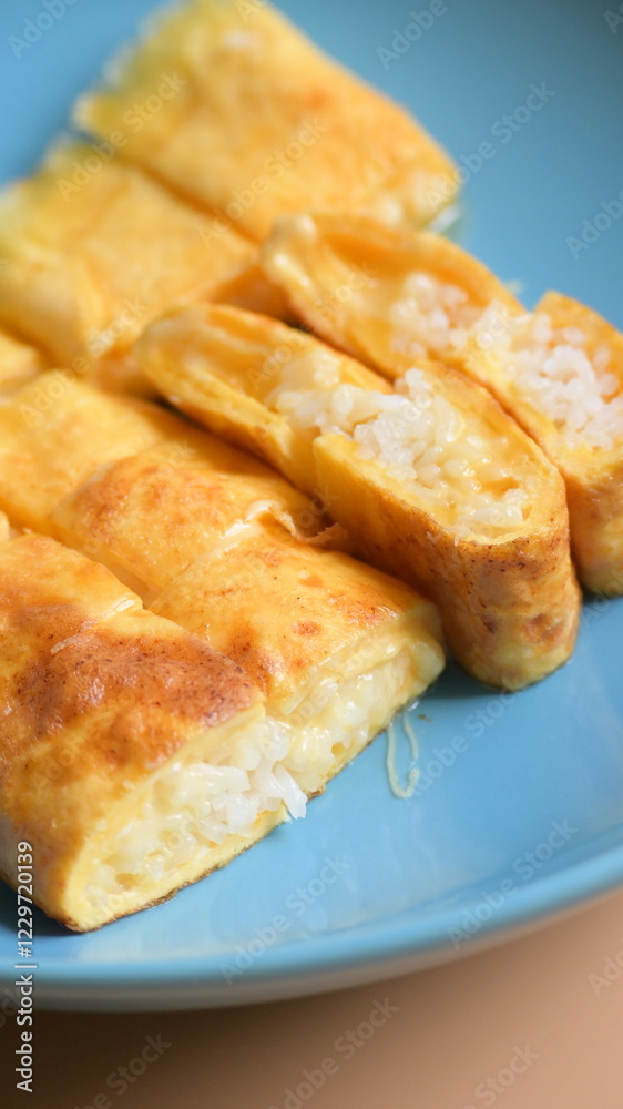 roll omelette stuffed with chesse and rice on blue plate, delicious food in the morning roll omelette stuffed with chesse and rice on blue plate, delicious food in the morning