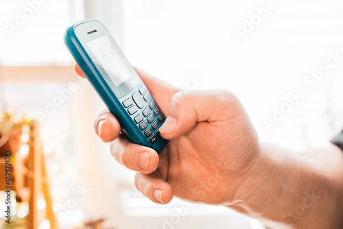 Man hold a dumbphone. An old phone. Digital minimalism concept.