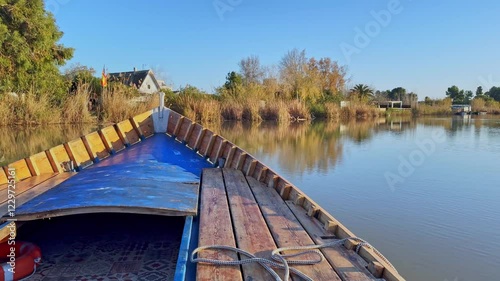 A wooden boat floating on a lake and in the distance you can see the fisherman's house