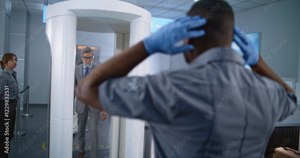 Naklejka premium Airport Terminal Security Check: Mature Businessman Passes Through Metal Detector Scanner. African American Security Officer Inspects Passenger for Boarding Flight. Diverse Travelers Going on Trips.