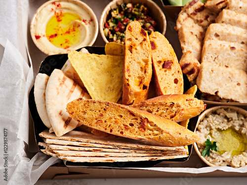 A vibrant platter features a variety of fresh flatbreads, including grilled and baked options, alongside tasty dips and sides for an enjoyable meal. Perfect for sharing with friends
