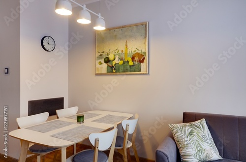 Salon w nowoczesnym apartamencie z beżową sofą, białym stołem z krzesłami photo