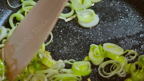 Food preparation. Chopped vegetables, leeks are fried in a hot pan with olive oil. Selective focus. Slow motion footage.