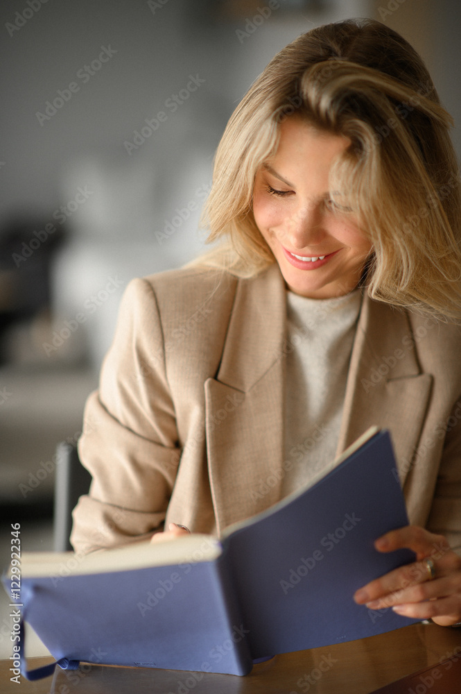 A businesswoman in a beige blazer working on a computer and making notes in a notebook, showcasing productivity, organization, and professional focus in a modern office setting A businesswoman in a beige blazer working on a computer and making notes in a notebook, showcasing productivity, organization, and professional focus in a modern office setting