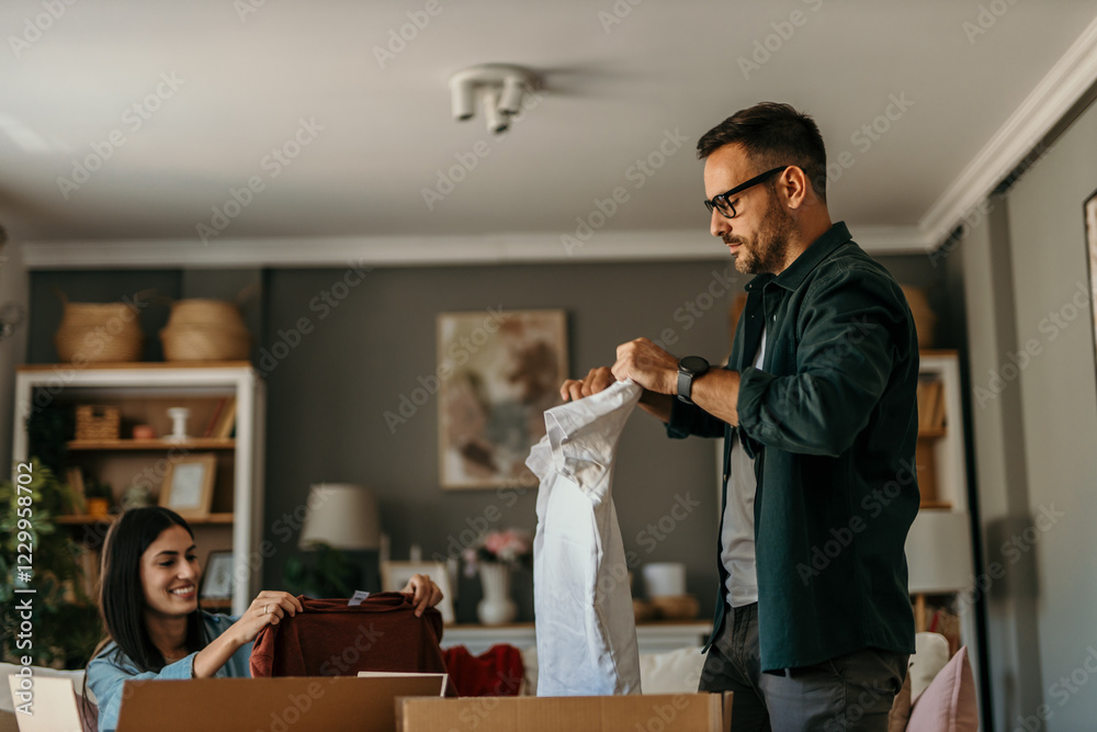 Obraz premium Man checking a sweater while woman packs clothes into a donation bag