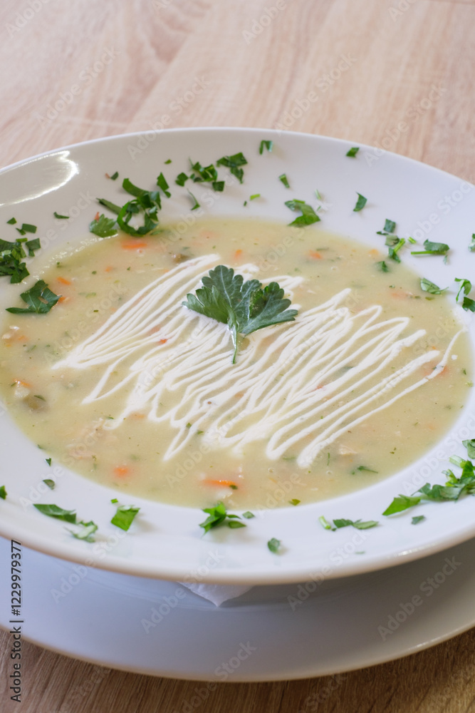 Creamy soup garnished with fresh herbs and a dollop of sauce Creamy soup garnished with fresh herbs and a dollop of sauce