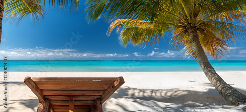 Fototapeta Naklejka Na Ścianę i Meble -  Wooden beach lounge chair on a white sand beach overlooking the ocean in a tropical location. 