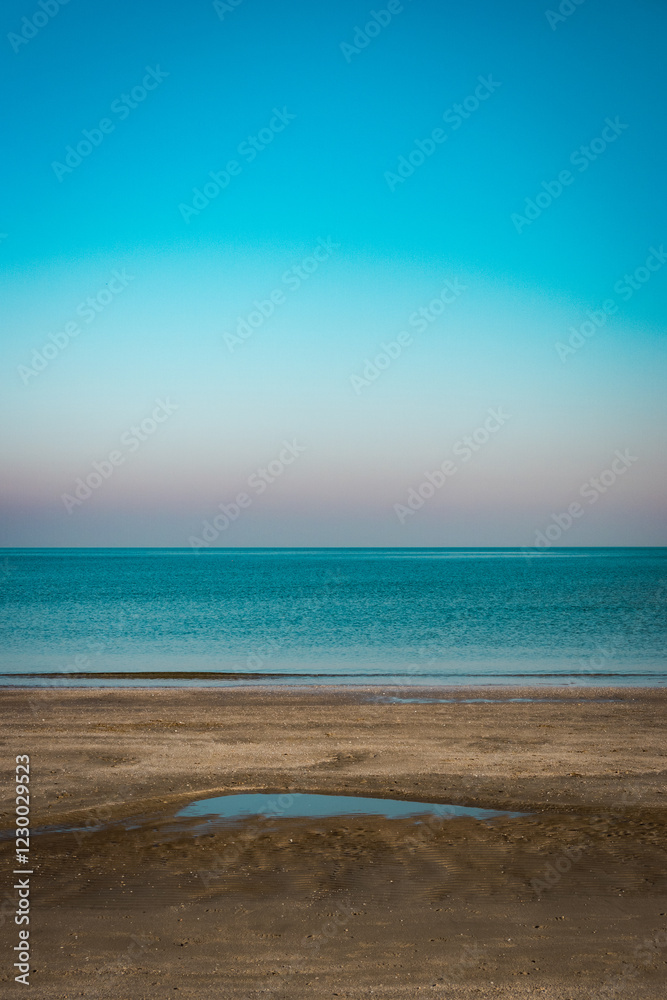 Fototapeta premium Serene beach with calm sea and clear blue sky