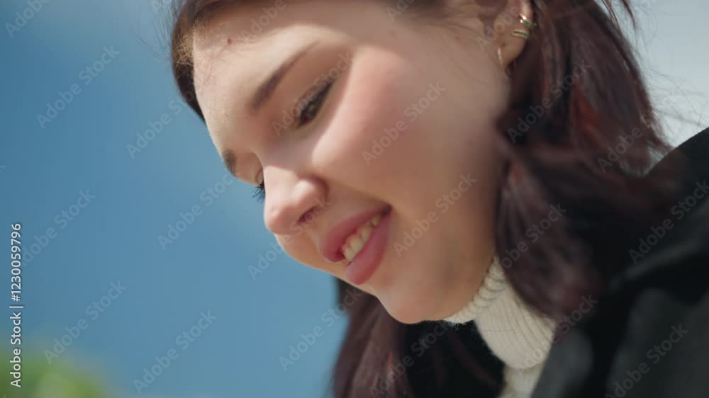 Close-up of woman smiling, earrings visible, hair swaying gently in the wind, radiating happiness, against a bright background with soft natural lighting Close-up of woman smiling, earrings visible, hair swaying gently in the wind, radiating happiness, against a bright background with soft natural lighting