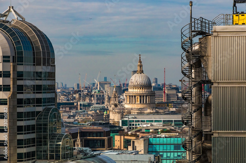 Great rooftop view of Ludgate Hill, the highest point of the City of London. The west front towers and the iconic dome of the famous St Paul's Cathedral are emerging from the surrounding buildings.