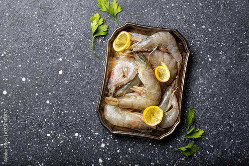  Raw shrimps in a plate and wooden board on the dark gray background top view photo