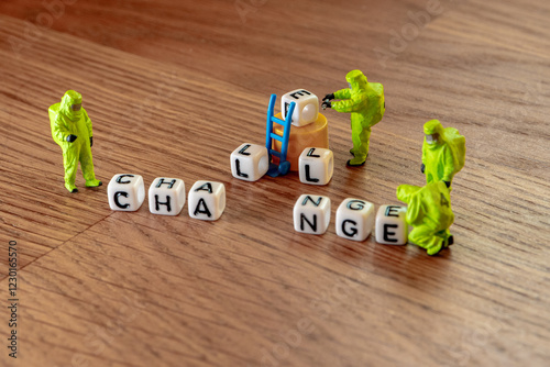 Removing white cubes with letters l and e of the word challenge creating new word change on wooden background with miniature figurines in hazmat biohazard suites photo