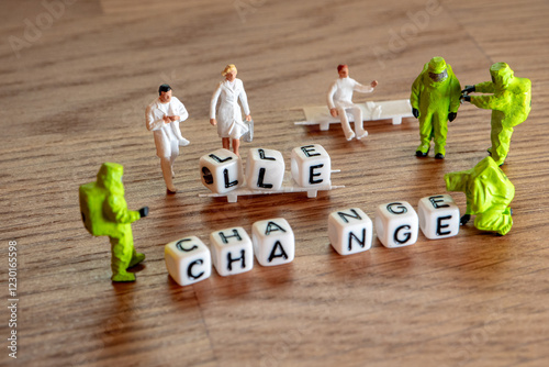 Removing white cubes with letters l and e of the word challenge creating new word change on wooden background with miniature figurines in hazmat and doctor suites  photo