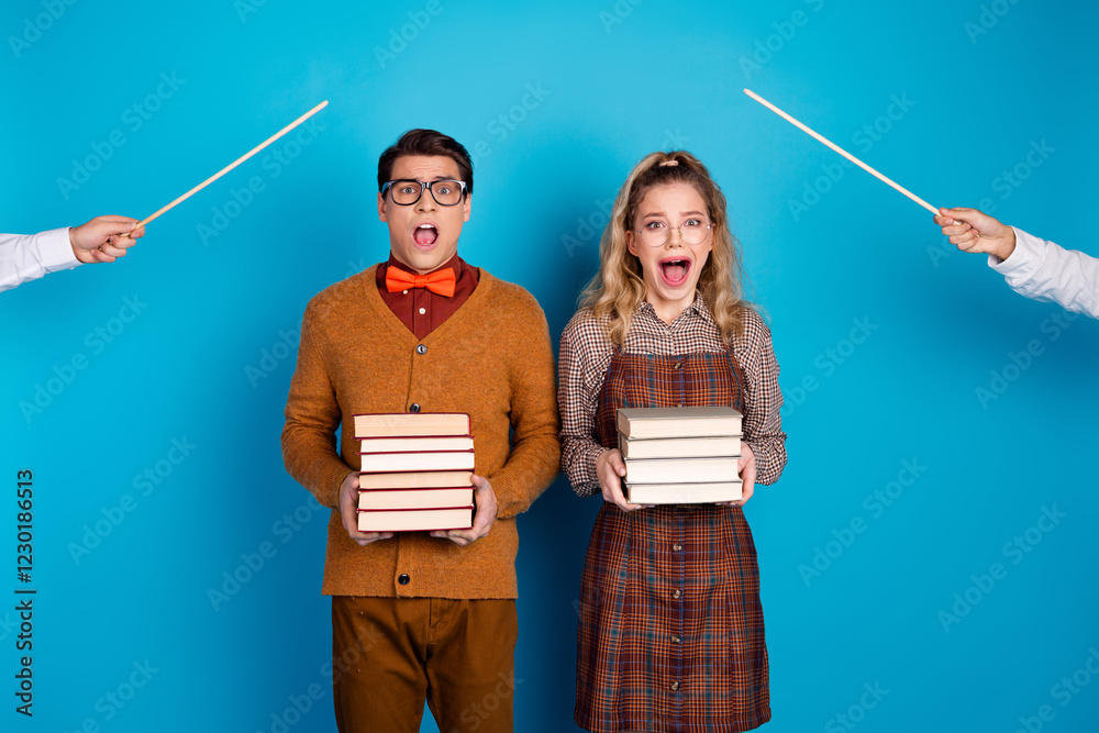 Young couple holding books in a humorous scene with retro clothing and blue background Young couple holding books in a humorous scene with retro clothing and blue background