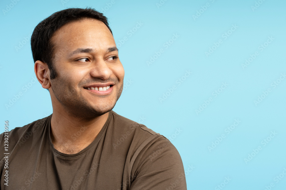 Fototapeta premium Smiling middle aged Indian man smiling and looking away on blue background