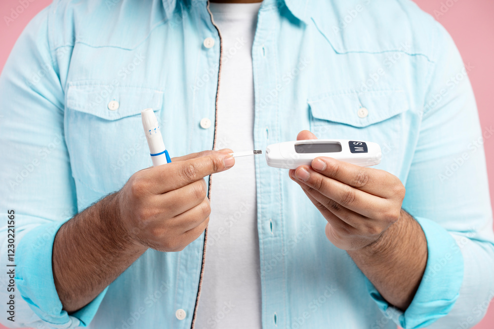 Man using lancing device and blood glucose meter for diabetes control Man using lancing device and blood glucose meter for diabetes control
